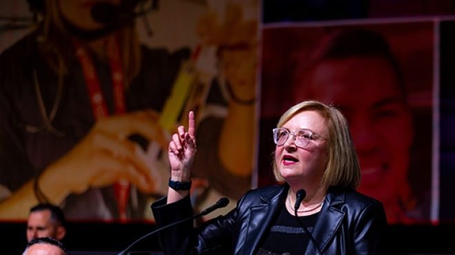 A woman speaks at a red Unifor podium.