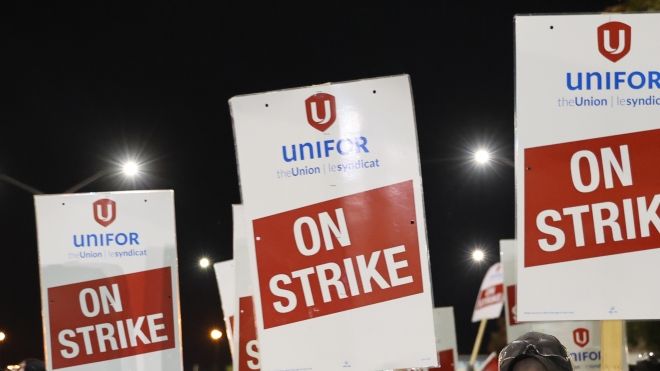 Four on strike signs being help up in the night sky