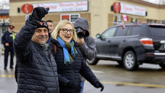 Two people walking down a road, one has fist raised in air.