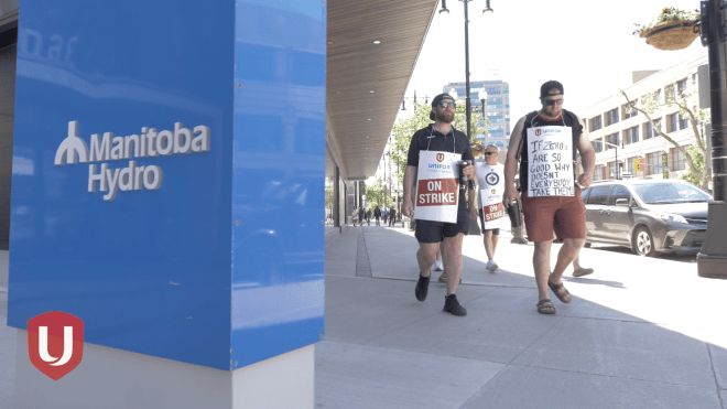 Members of Unifor Local 681 walking a picket line with the Manitoba Hydro Place sign in the foreground