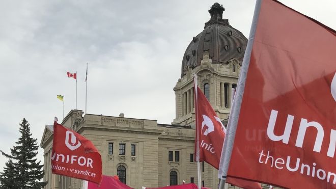 Unifor flags wave in front of the Saskatchewan legislature building.