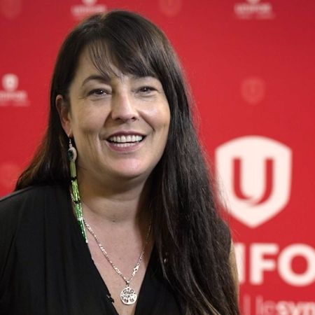 An indigenous women smiling in front of a red Unifor backdrop