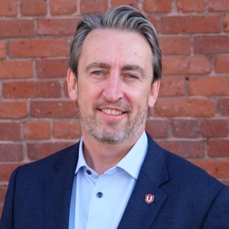 Gavin McGarrigle standing in front of a red brick wall