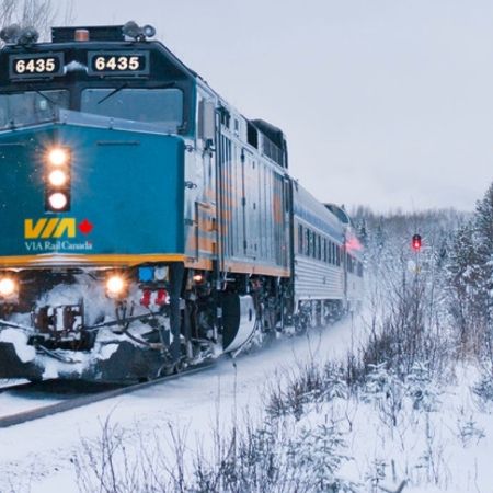 Via train on tracks snow covered trees 