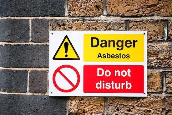 A sign on a brick wall reads &quot;Danger asbestos. Do not disturb.&quot;