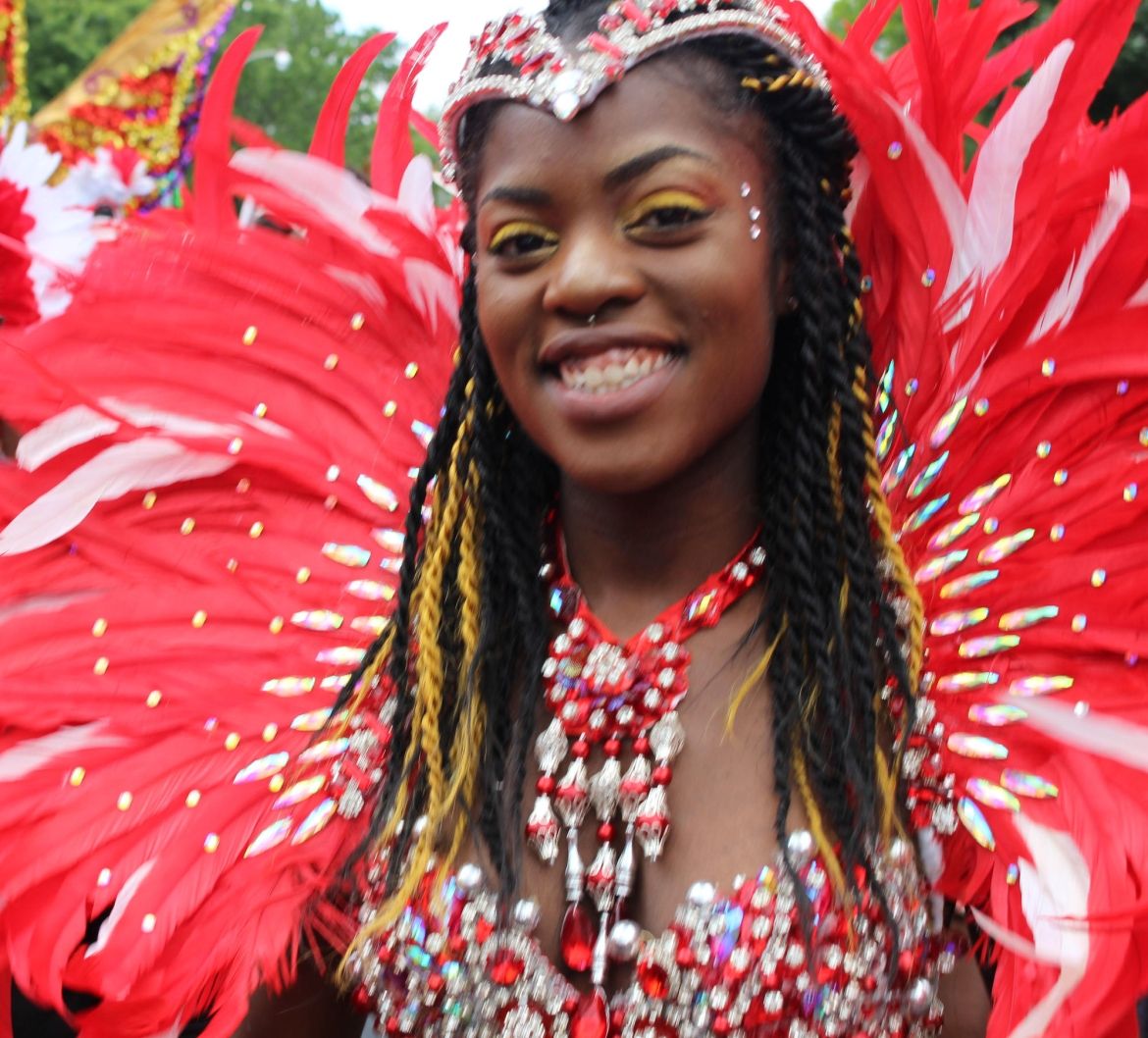 A participant in Toronto's Caribbean Carnival Parade is dressed in a red feathered and sequined outfit.