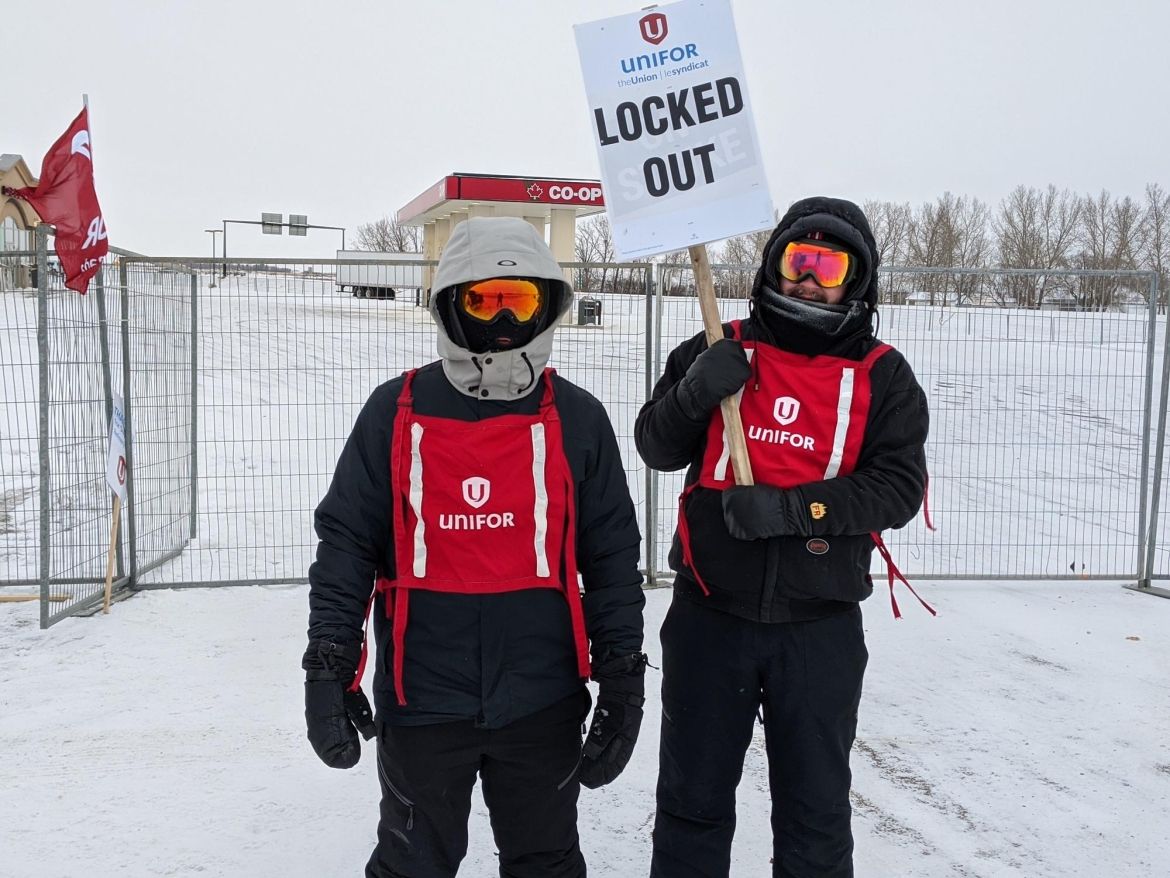 Co op members in snow suites with unifor vests holding a locked out sign.