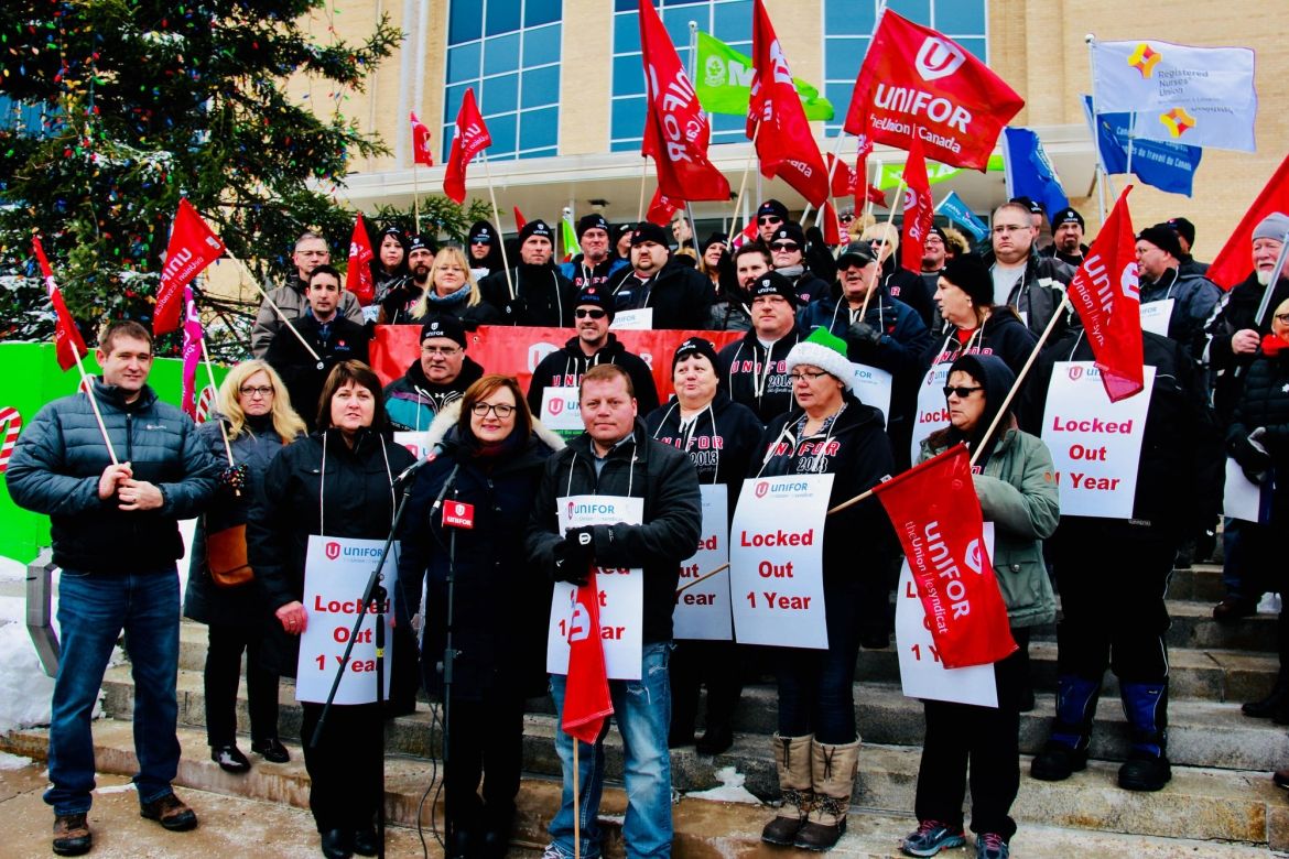 Lana Payne and members of Local 597 hold signs and banners on the steps of Newfoundland and Labrador's confederation building.