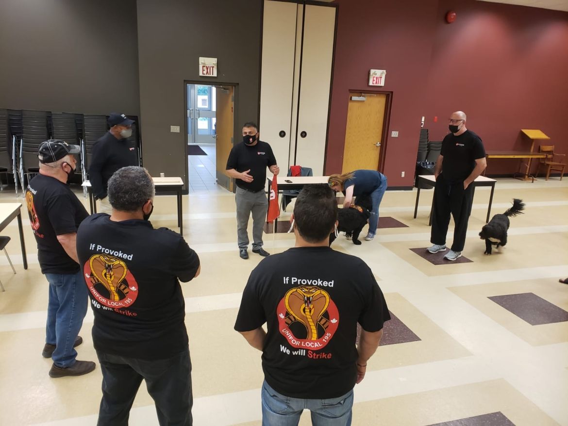 7 workers gather in a cirrcle 6 feet apart in a meeting hall