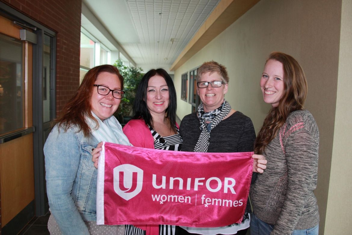 Four Unifor sisters hold a Unifor Women's flag.