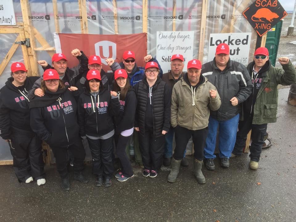 Des memberes de la section locale 597 lèvent le poing en signe de solidarité sur leur ligne de piquetage chez D-J Composites.