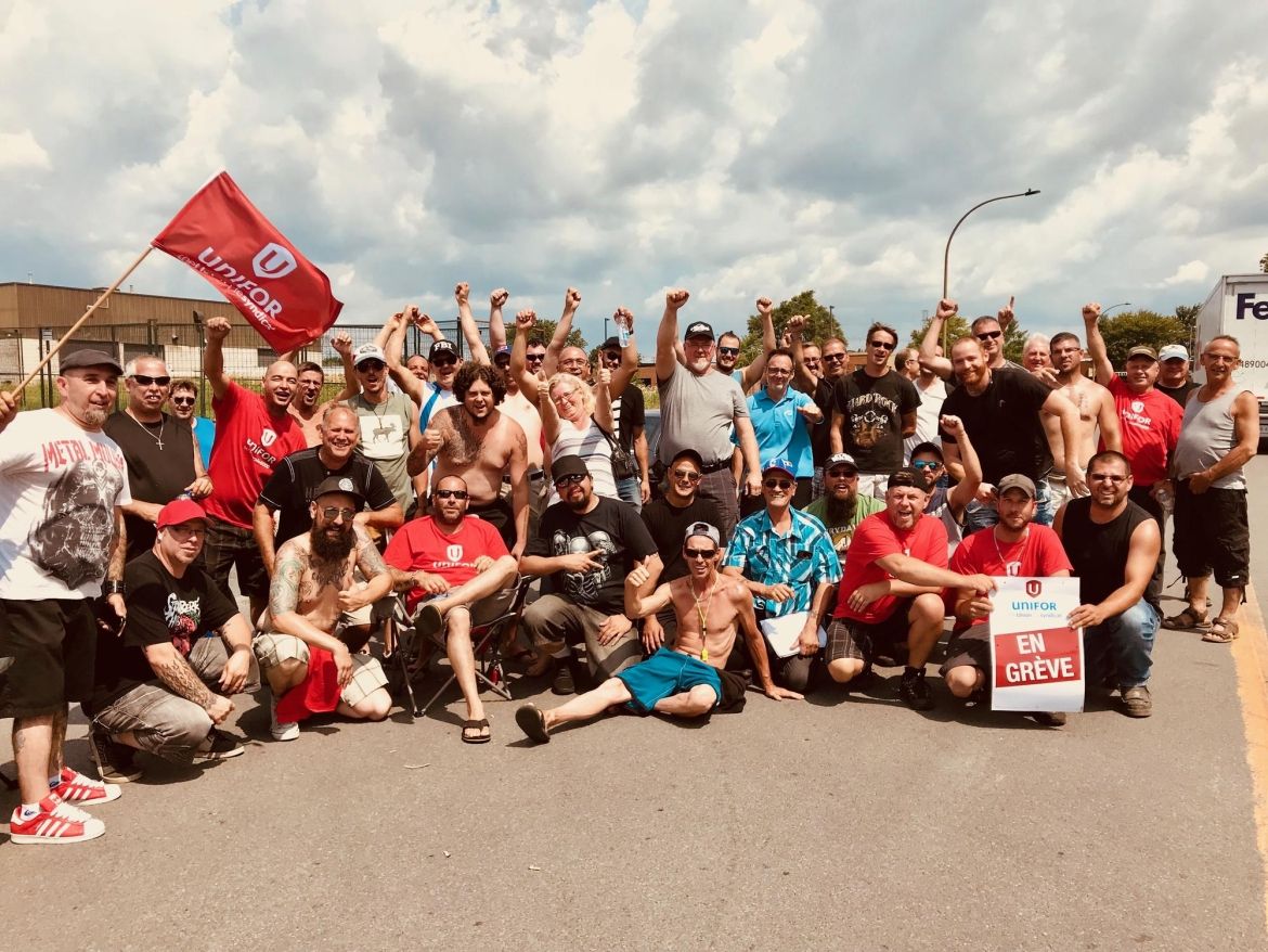 Members of Unifor Local 6000 raise their fists in solidarity on a picket line at Oldcastle BE.