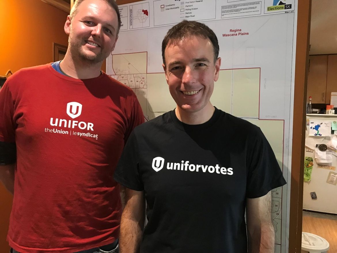 Deux membres d'Unifor devant une carte électorale.