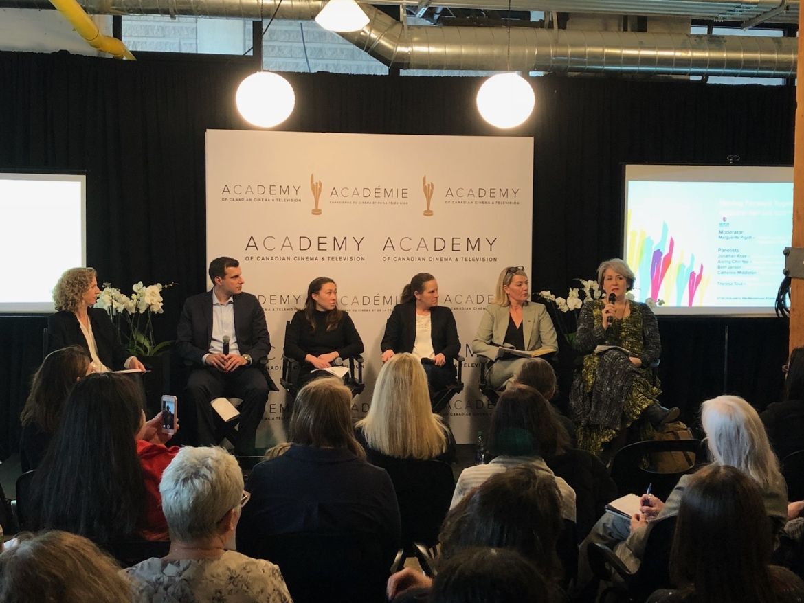 Panelists take part in a discussion while seated in front of a backdrop bearing the logo fo the Academy of Canadian Cinema and Television.