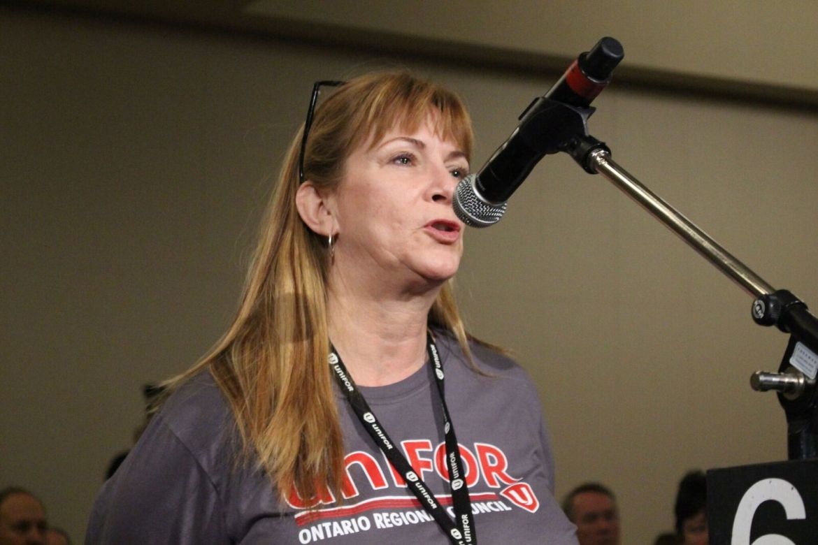 A Unifor member, wearing an Ontario Regional Council shirt, speaks to a crowd of people.