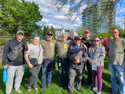 Eight people in Unifor shirts pose outside on a sunny day