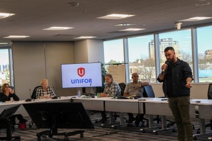 A man speaks into a mic in front of a room.