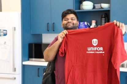 A man holding up a red Unifor t-shirt