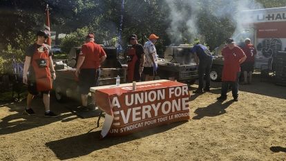 several people standing in front of smoking BBQ's
