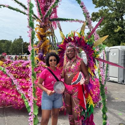 Samia Hashi standing in front of a parade float with a woman dressed in parade wear