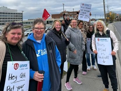 A large group protesting on the side of a road a few wearing placards