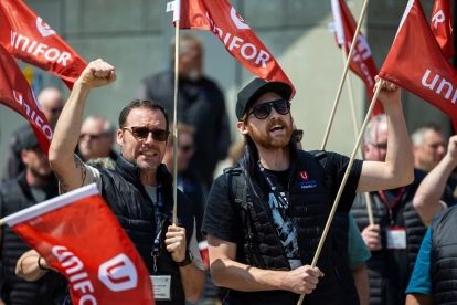 A group holding up red Unifor flags cheering