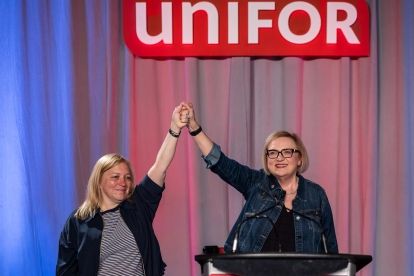 Two women at a podium holding hands raised up.