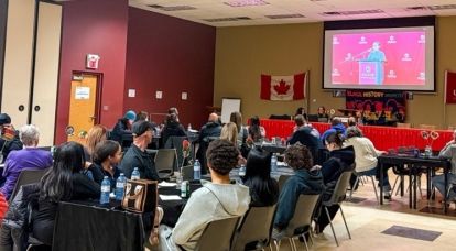 People sitting at tables looking at a presentation screen.