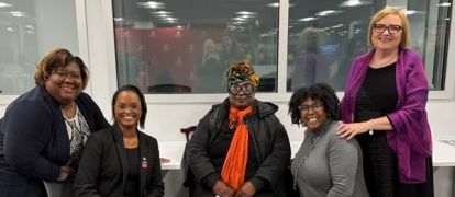 Five women posing smiling.