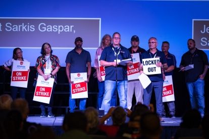 people on stage holding on strike signs