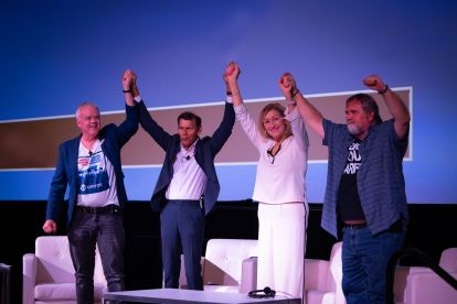 Four peolp on stage holding up their hands held