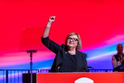 Lana Payne speaking at a podium with a fist raised