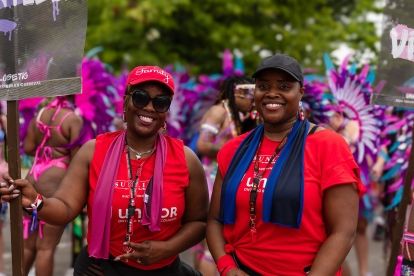 Two women in red shirts one holding a sign