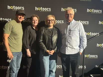 four people posing in front of a hotdocs banner