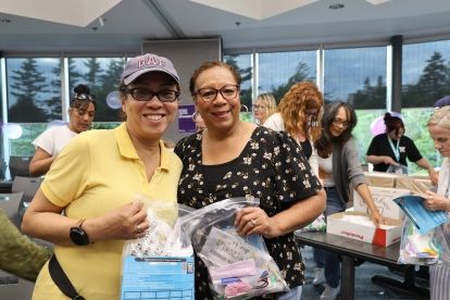 Two women smiling holding up kits in clear bags