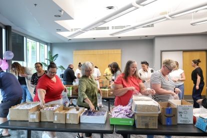 A group of women walking around tables collecting materials for kits