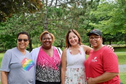 Four women pose smiling