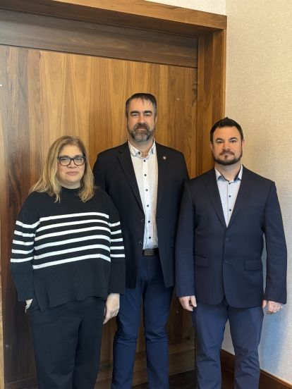 Three people smile to camera at the Bell AGM