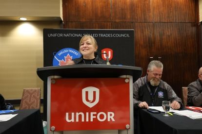 women speaking at a podium with Unifor logo