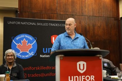 Man speaking at a podium with Unifor logo