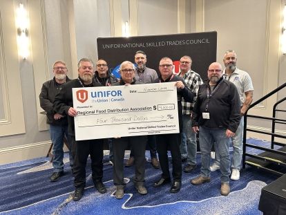 A large group posing with an oversized cheque