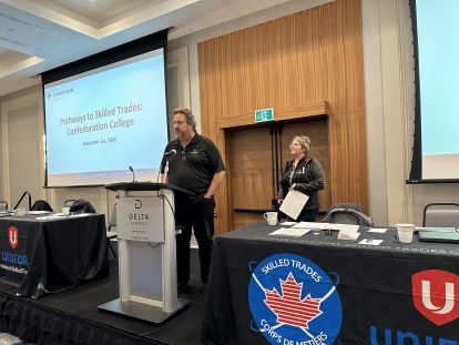 a man standing at a podium with a screen in the background