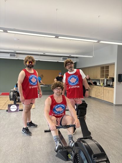 Three men in costumes one on row machine