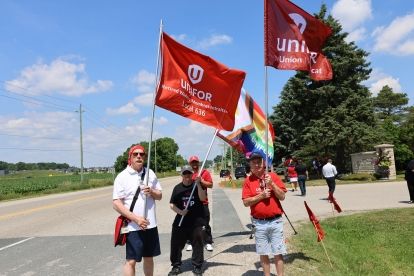 people walking at roadside carrying flags