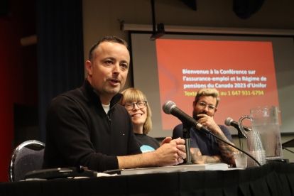 a man speaking into a mic in front of a presentation screen