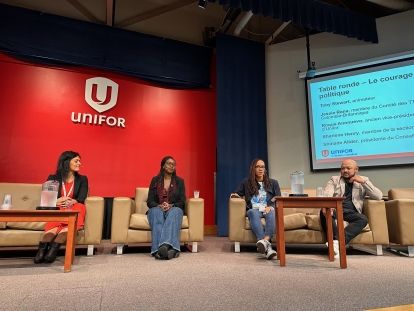 A panel of four on stage infront of a red Unifor screen