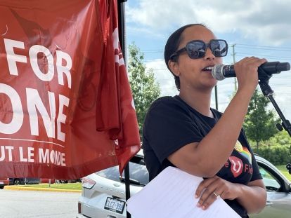 women speaking with red sign in background