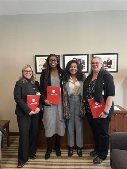 Four women smiling holding red Unifor folders