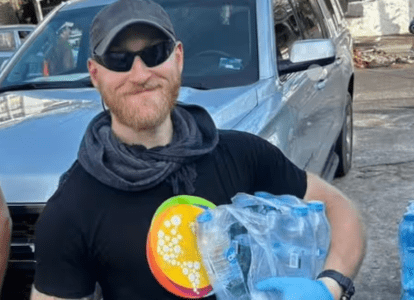 A man wearing sunglasses and hat carries plactic garbage