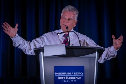 man at podium with arms raised